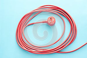 Coiled red electrical cable or lead with plug
