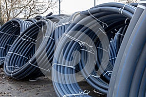 Coils of black polyethylene pipes for laying high voltage electrical cables underground at a construction site