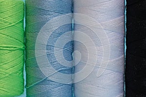 Coils with black, white, blue and green threads on a blue background