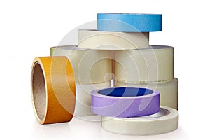 Coils of plastic and paper adhesive tape, on white.