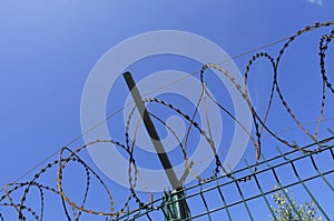 Coils of razor wire on a metal fence with a crossbar