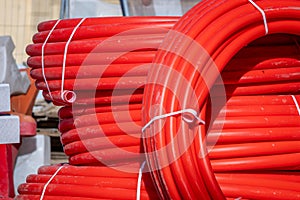 Coils of red polyethylene pipes for laying high voltage electrical cables underground. Construction site with city. Red