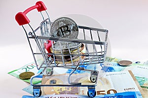 Coin of the cryptocurrency bitcoin in a basket from a supermarket against the background of paper bills from