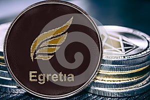 Coin cryptocurrency EGT Egretia on the background of a stack of coins.