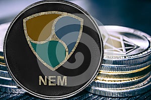 Coin cryptocurrency NEM XEM on the background of a stack of coins.