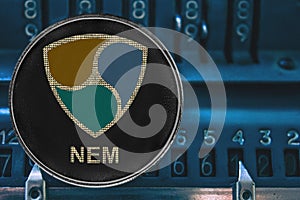 Coin cryptocurrency NEM XEM against the numbers of the arithmometer.