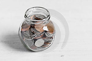 Coin jar on a white table top, money savings concept with copy space