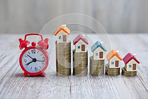 Coin ladder.Stacking coins on desk with clock. Finance and money concept.Stacked coins to save for the house with wooden table