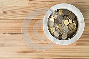 Coin money in marble ashtray on natural wooden background