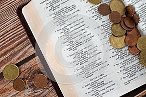 Coin money on open Holy Bible, concept of Christian tithing, offering, religious contribution