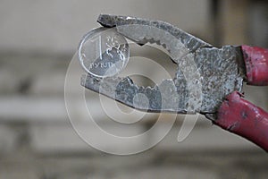 Coin one Russian ruble clamped in a pliers