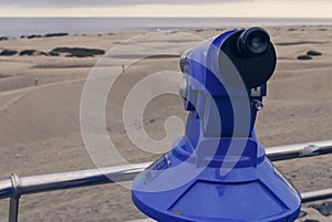 Coin-operated binocular looking out sand desert dunas