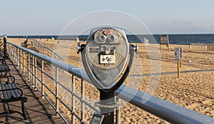 Coin operated binoculars on the boardwalk overlooking a beach