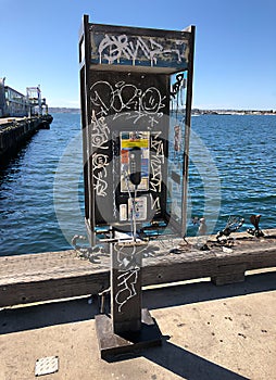 Coin operated Phone booth w graffiti by the ocean