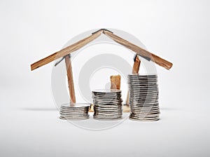 Coin stack and house miniature isolated on white