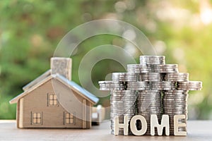 Coin stack with house model, home message, savings plans for housing ,green background, financial concept