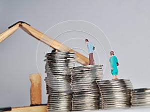 Coin stack,miniature people  and house miniature  on white