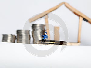 Coin stack,miniature people and house miniature  on white