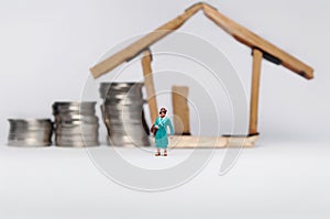 Coin stack,miniature people and house miniature  on white