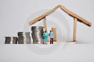 Coin stack, ,miniature people and house miniature  on white