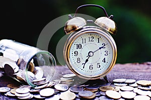 Coin stacks arranged into business cycle step, up and down, and vintage alarm clock on wooden table with morning light