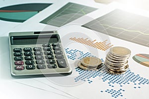 Coin stacks and calculator on paper of financial graph. Business