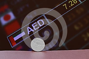 The coin of United Arab Emirates one dirham money on obverse on brown floor with digital board of currency exchange money