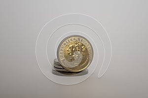 A coin worth ten lipa stands upright on another coin