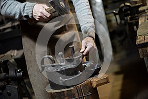 Coinage craftsman stamping coins with hammer and anvil. photo