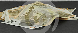 Coins and banknotes lying o a black surface