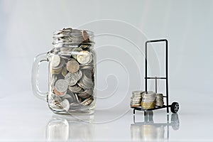 Coins in classic glass jar and coins in cart on white background saving and investment concept