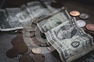 Coins and dollar bills scattered on concrete table