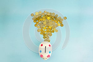 Coins falling behind a piggy bank