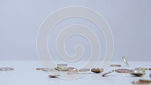 Coins falling on white surface slow motion