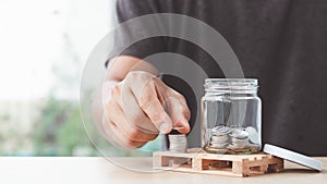 Coins in a glass bottle, Male hand putting coin with money stack step growing growth saving money,