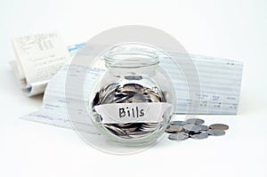 Coins in glass container with Bills label with bills receipts is photo