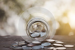Coins in glass jar and on coins on wood,thinking for future,house,finance,education