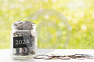 Coins in glass jar. Collect money for future, saving and investment in 2024 concept. Closeup, copy space