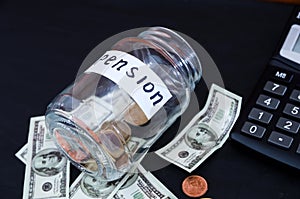 Coins in a glass jar, dollars and calculator on black. Saving money. Pension concept.