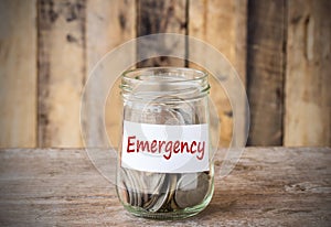 Coins in glass money jar with emergency label, financial concept