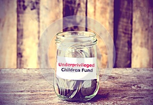 Coins in glass money jar with Fund for Underprivileged Children photo