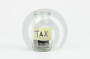 Coins in glass money jar with tax label, financial concept.