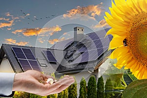 Money on hand against a house with solar panels installed on the roof. Economic benefits of renewable energy. Conceptual image