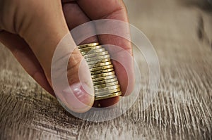 Coins in hand on a wooden table background, close-up.