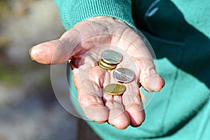 The coins are in the hands of the old lady. An elderly woman with money in her hands. Poverty alms