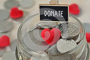 Coins and heart in glass money jar with Donate label - Charity concept