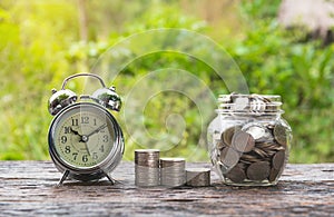 Coins in jar with money stack step growing money and alarm clock