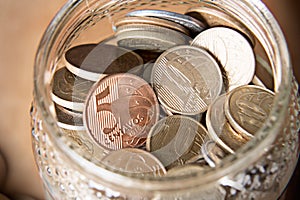 Coins in a jar with a wooden table