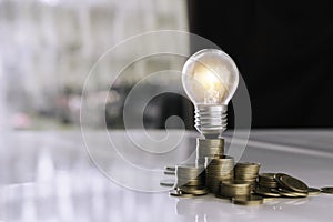 Coins and light bulb on table for saving money,energy concept