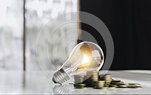 Coins and light bulb on table for saving money,energy concept